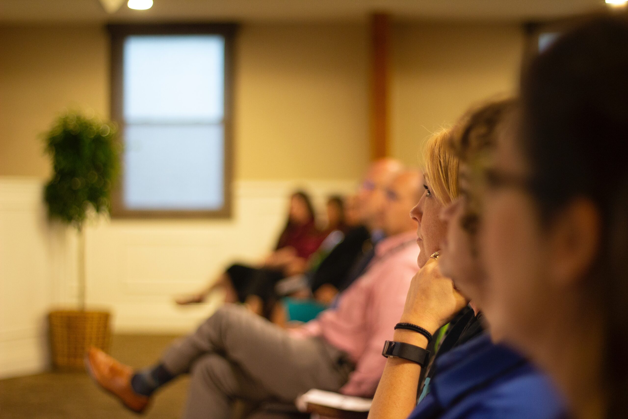 Bilden visar personer som sitter i ett möte eller en konferens. Det finns fällbara konferensbord och andra fällbara stolar till konferenser och möten.